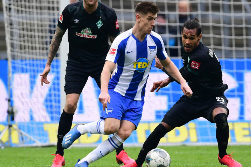 Krzysztof Piatek (M) von Hertha im Zweikampf mit Bremens Theodor Gebre Selassi (r).