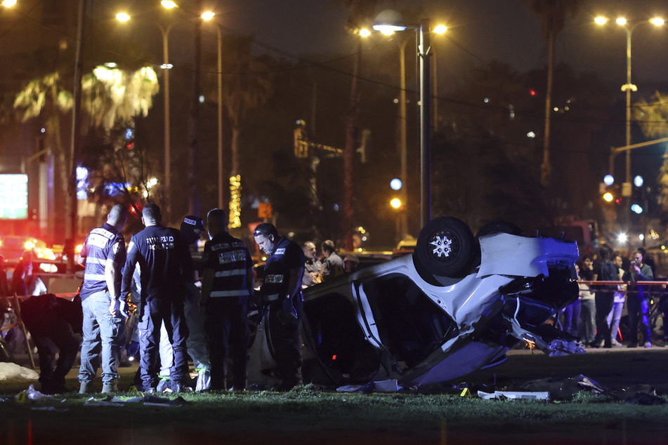 Die israelische Polizei und der Rettungsdienst stehen neben dem Auto, das den Anschlag verübte.