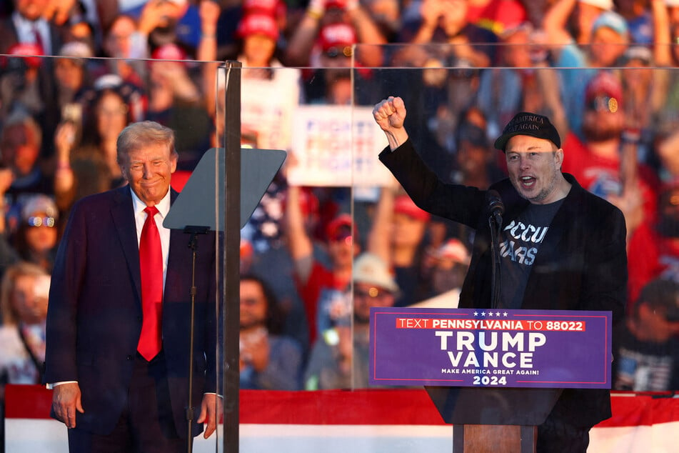 Tesla CEO and X owner Elon Musk speaks as Republican presidential nominee Donald Trump looks on during a rally in Butler, Pennsylvania, on October 5, 2024.