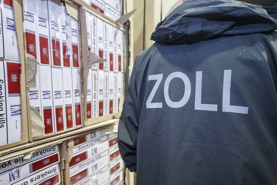 Ein Zollbeamter steht vor konfiszierten Paletten mit geschmuggelten Zigaretten. (Archivbild)