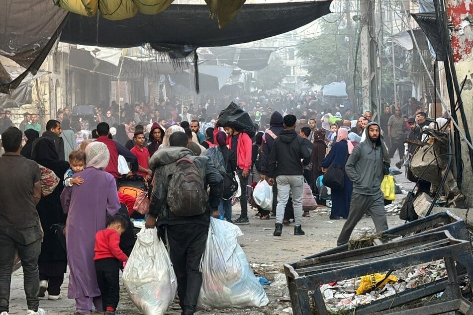 Palestinians walk down a street with their belongings after fleeing their homes in Beit Lahia, in the northern Gaza Strip, on October 22, 2024.