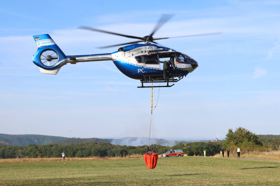 Weil das Gelände schwer zugänglich ist, wurde ein Polizeihubschrauber angefordert, der mit einem abwerfbaren 820 Liter-Wasserbehälter ausgestattet ist.