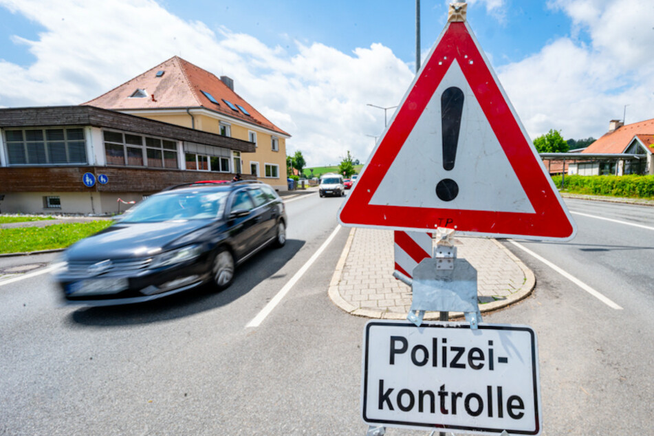 Autos fahren an der deutsch-tschechischen Grenze hinter einem Schild mit der Aufschrift "Polizeikontrolle" Richtung Tschechien.