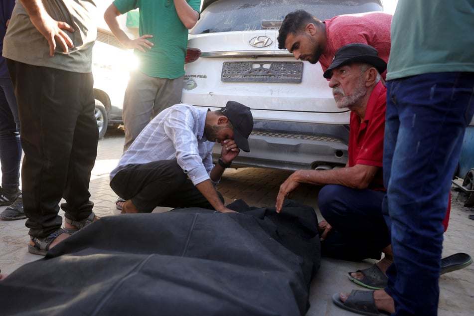 Friends and relatives mourn over the shrouded body of a man killed in an Israeli strike, as he is brought to Deir al-Balah's Shuhada al-Aqsa hospital in the central Gaza Strip on October 19, 2025.