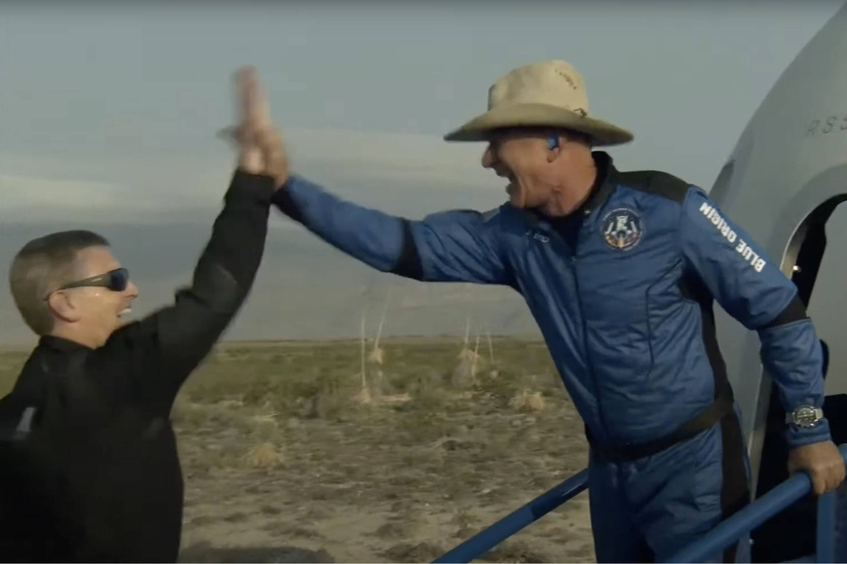 Blue Origin and Amazon founder Jeff Bezos (r.) exists the crew capsule after landing in the desert of west Texas on Tuesday.