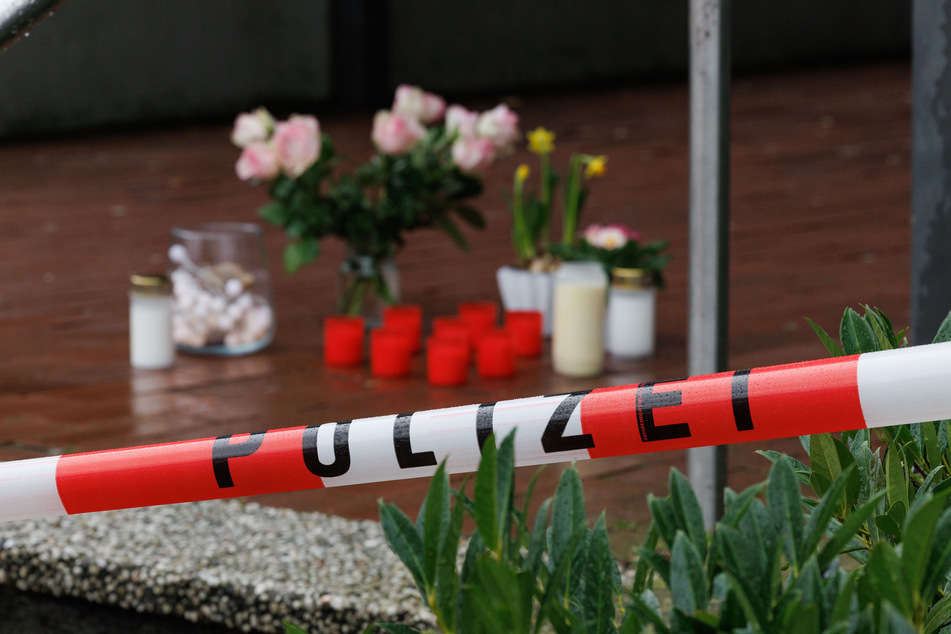 Trauerkerzen und Blumen stehen vor dem polizeilich abgesperrten Eingang des Berufskollegs Tecklenburger Land.