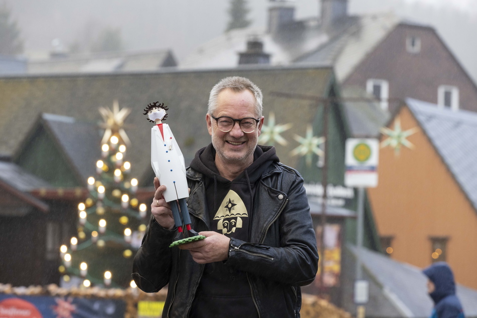 Tino Günther (59) hält ein Räuchermännel, das dem Virologen Drosten nachempfunden ist, vor dem Seiffener Sternemarkt in die Höhe. Die Figur ist ein Verkaufshit.