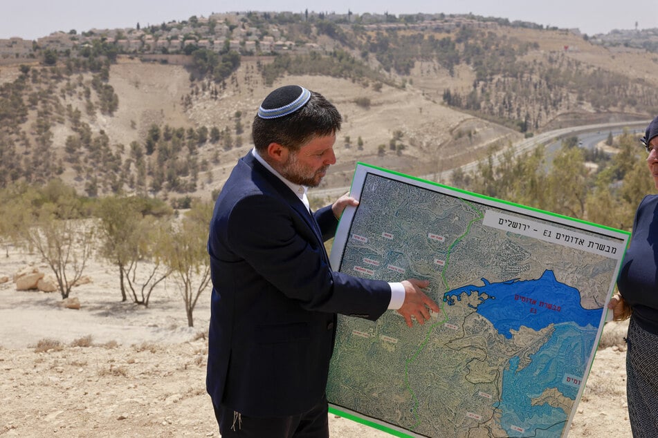 Israeli far-right Finance Minister Bezalel Smotrich holds a map of an area near the settlement of Maale Adumim, a land corridor known as E1, outside Jerusalem in the occupied West Bank, on August 14, 2025.