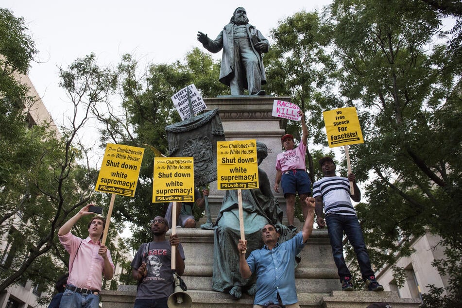 Demonstrators hold signs calling for an end to white supremacy while standing in front of the statue of Confederate General Albert Pike in Washington DC.