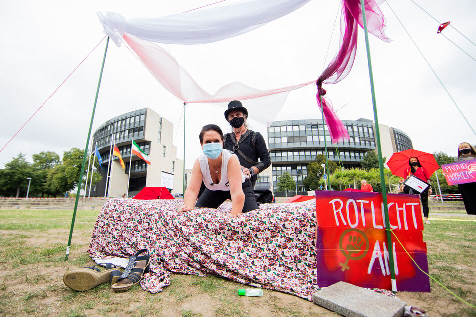 Thomas und Nicole, Straßen-Sexarbeiterin, demonstrieren auf einem Bett vor dem Landtag, wie bezahlte Sexangebote während der Corona Pandemie aussehen könnten.