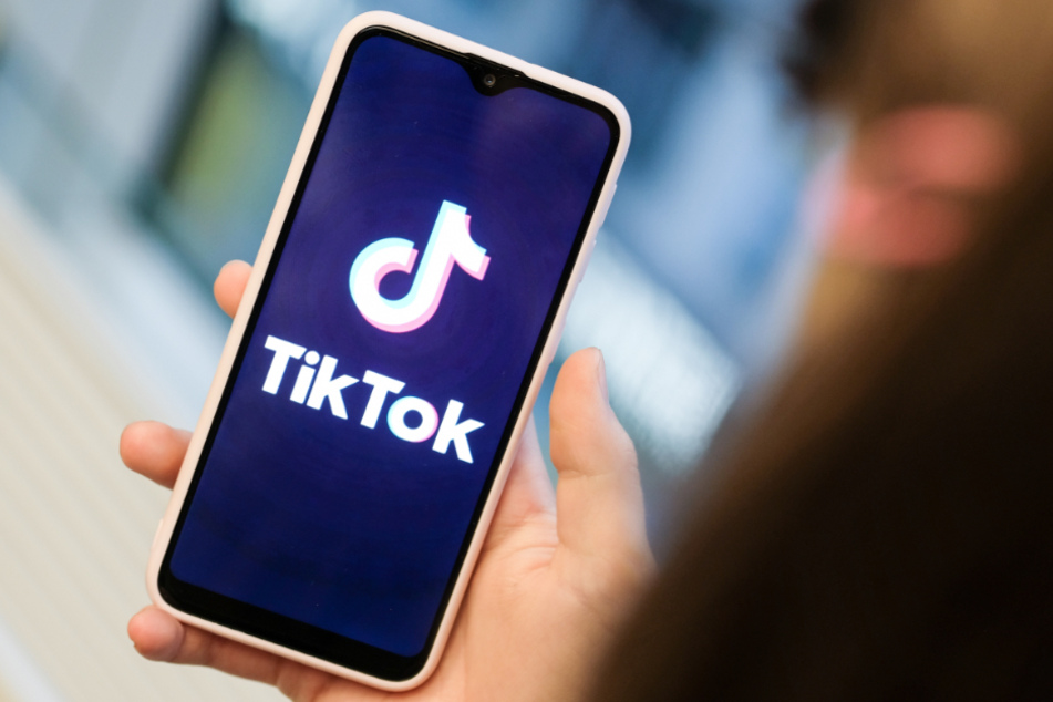 Ein Mädchen hält ihr Smartphone in den Händen, auf dem sie die Kurzvideo-App TikTok geöffnet hat.
