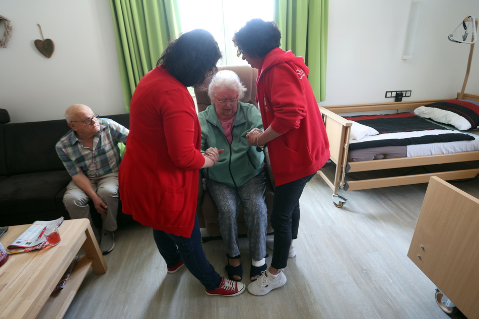 Zwei Pflegerinnen helfen einer Seniorin aus dem Sessel. Der Millionenbetrug schädigt auch die verantwortungsvoll arbeitenden Dienste.