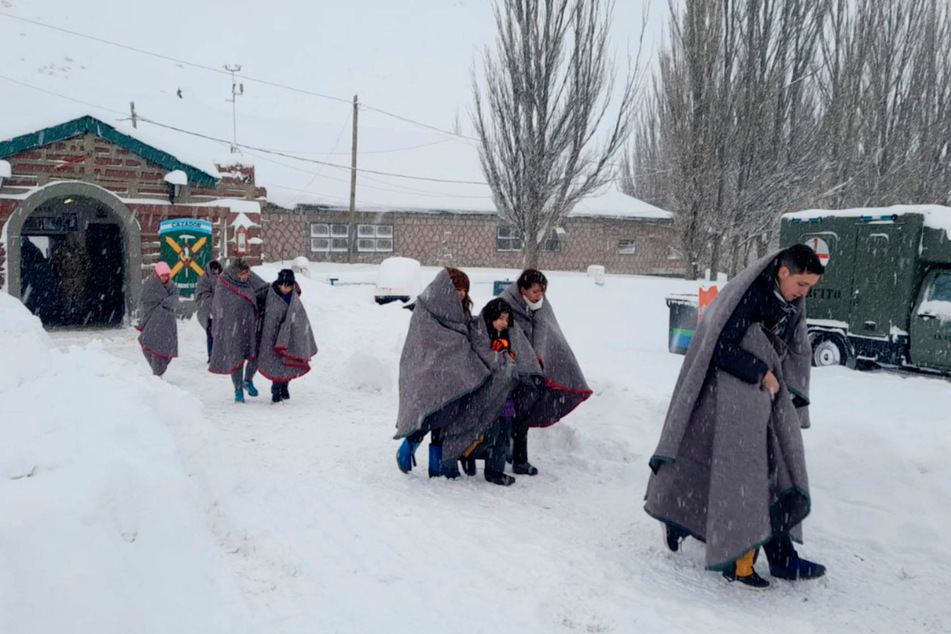 Am 10. Juli werden Menschen, die in Decken umhüllt sind, nach einem starken Schneesturm in den Anden zwischen Argentinien und Chile evakuiert.