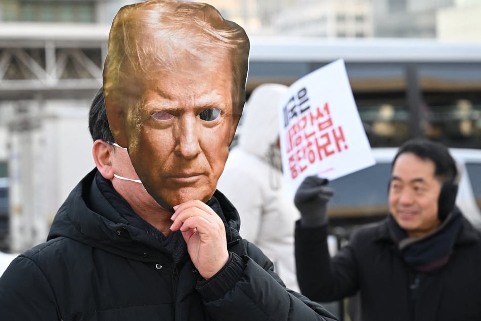 A protester wears a mask of Donald Trump during a rally condemning US president's plans to raise tariffs on South Korea in front of the US embassy in Seoul on January 27, 2026.