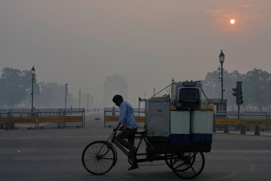 Ein Radfahrer tritt nahe des India Gate Monument in die Pedale.