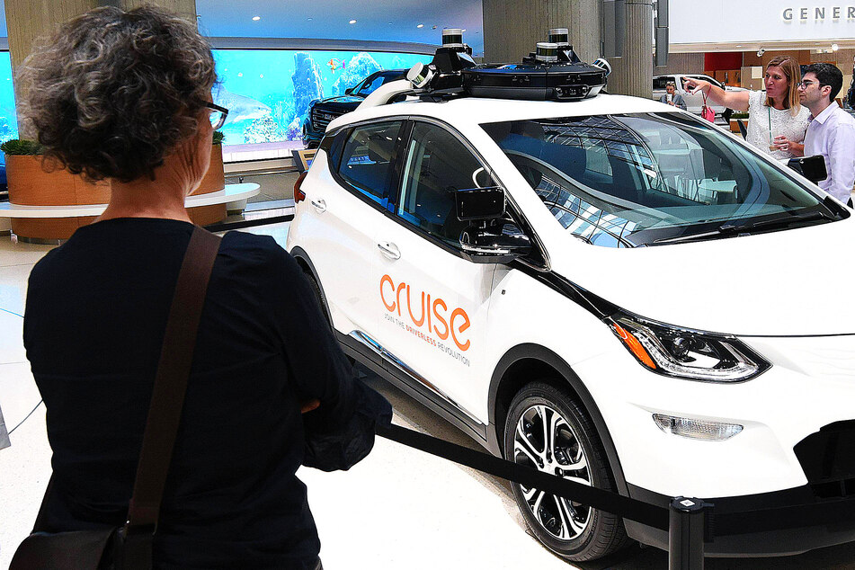 People admire a GM Cruise self-driving car on display at the General Motors world headquarters building in Detroit's Renaissance Center.