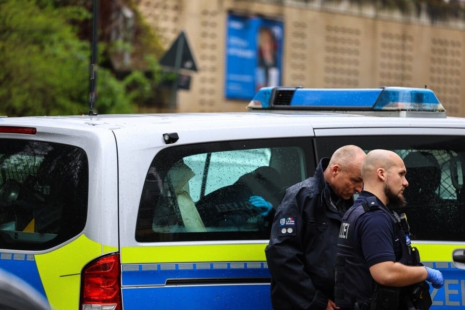Zwei Polizisten stehen während eines Großeinsatzes in Witten neben einen Einsatzwagen.