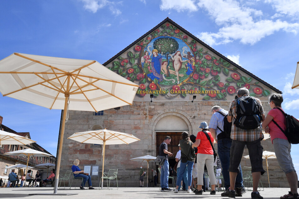 Besucher stehen am Giebel der Peterskirche auf dem Gelände der Bundesgartenschau auf dem Petersberg in Erfurt. Das Zwischenfazit nach den ersten Monaten fällt positiv aus.