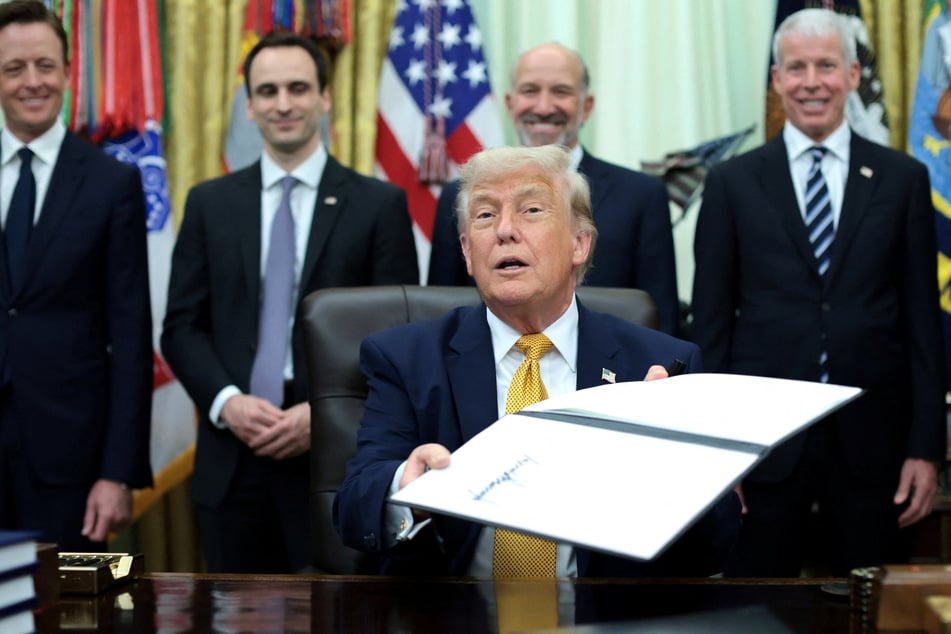 President Donald Trump holds up a signed executive order regarding quantum computing in the Oval Office of the White House on June 22, 2026.