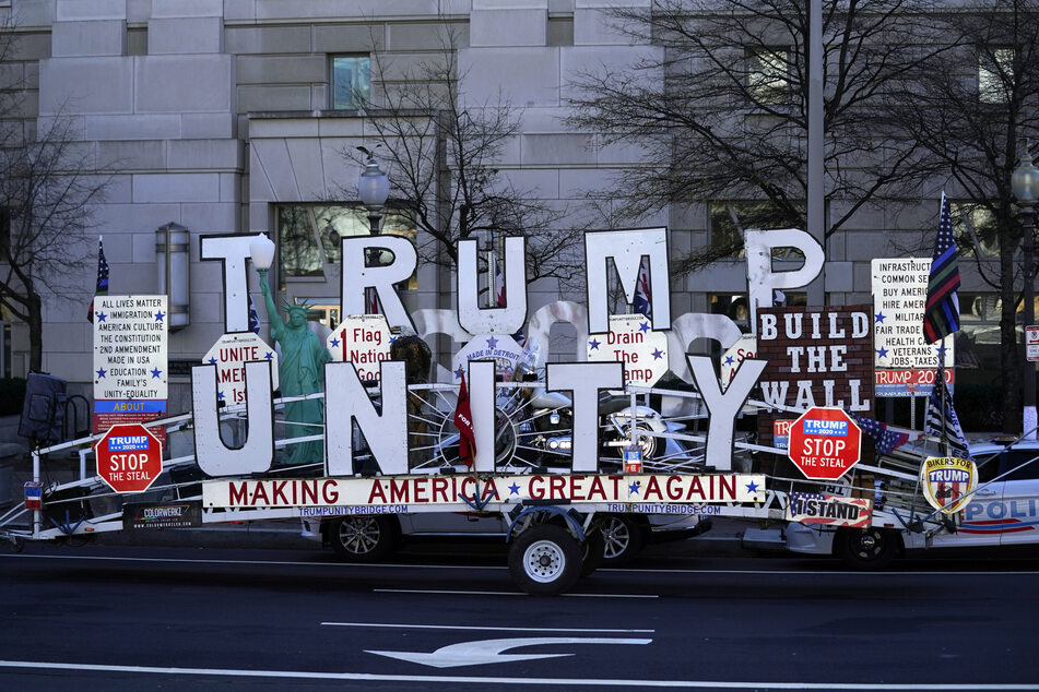 Ein Unterstützer des scheidenden US-Präsidenten Trump ist mit einem Anhänger unterwegs, auf dem "Trump Unity" (Trump-Einheit) und verschiedene Parolen wie "Build the Wall" (Baut die Mauer) oder "Making America Great Again" (Amerika wieder groß machen) zu lesen sind.