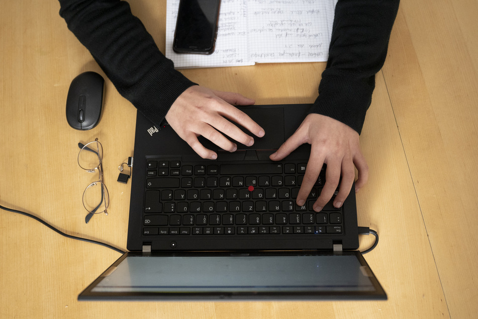 Eine Frau arbeitet am Tisch an ihrem Laptop.