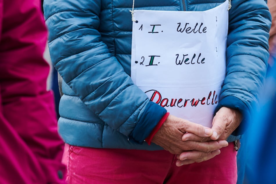 "1.Welle - 2.Welle - Dauerwelle" steht auf dem Plakat einer Demonstrantin bei einer Querdenken-Demo.