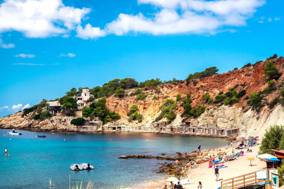 Menschen genießen die Sonne am Cala d'Hort Strand auf Ibiza.