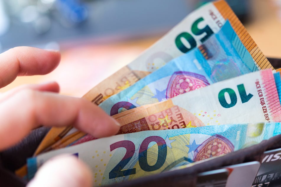 Eine Frau hält eine Geldbörse mit Banknoten in der Hand.