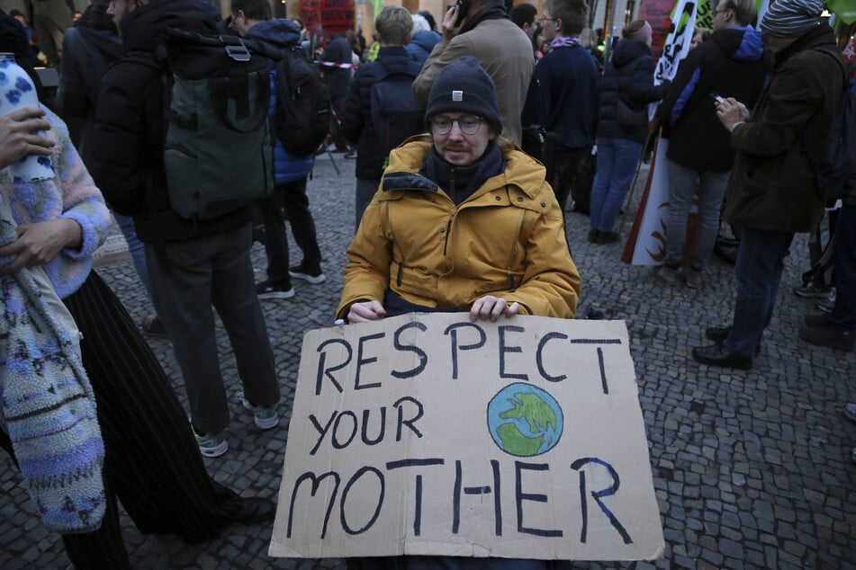A man holds a sign reading "Respect Your Mother" during a Fridays for Future demonstration on November 14, 2025.