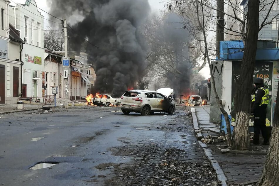 Autos brennen und Rauch steigt auf, nachdem ein russischer Raketenangriff das Stadtzentrum von Cherson getroffen hat.