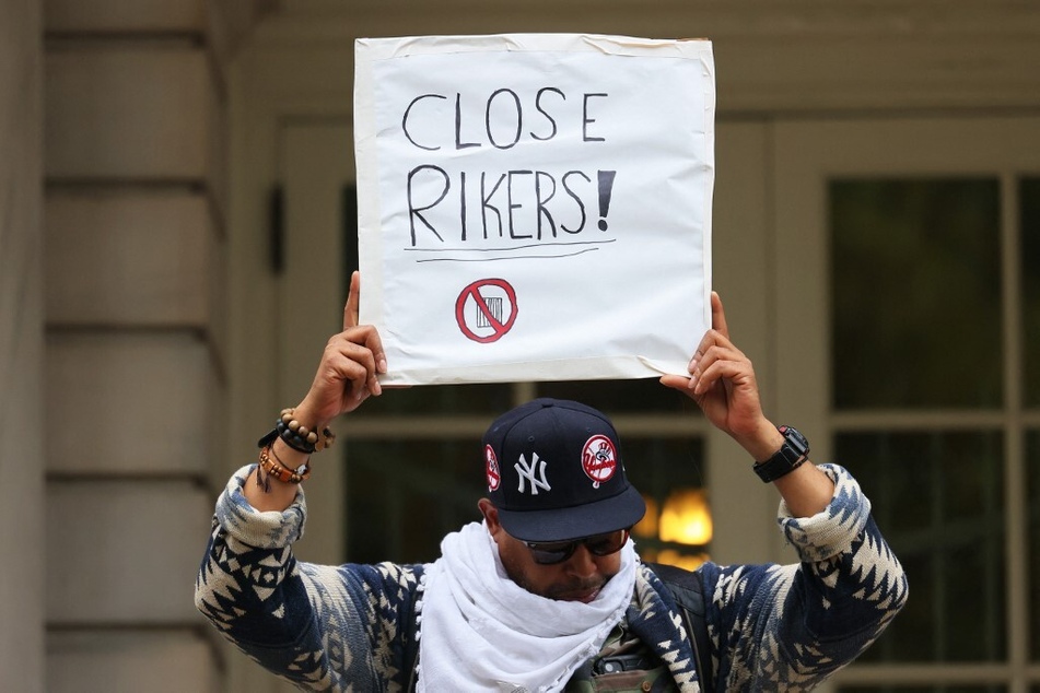 A protester holds up a sign calling for the closure of Rikers Island outside New York City Hall.