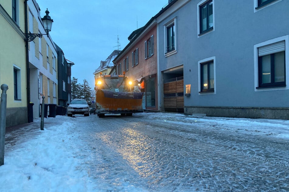 Ein Winterdienstfahrzeug fährt in Dachau auf eisglatter Straße durch die Stadt.