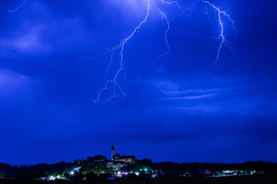Ein Gewitter entlädt sich in Oberbayern hinter der Kulisse des Kloster Andechs auf dem Heiligen Berg.