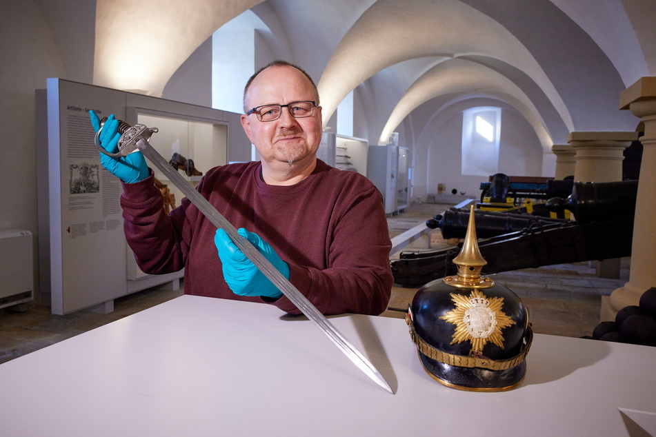 Museumsmitarbeiter Ingo Busse zeigt einen Offiziersdegen von 1863 und eine Pickelhaube von 1897. Die Exponate sind Teil der Wanderausstellung, die zuerst in China präsentiert wird.