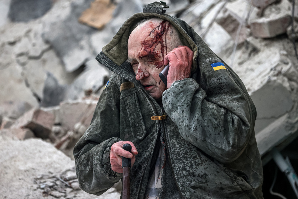 Opfer russischen Raketen-Terrors: Ein älterer Mann telefoniert nachdem er aus den Trümmern seines völlig zerstörten Wohnblocks gerettet wurde.