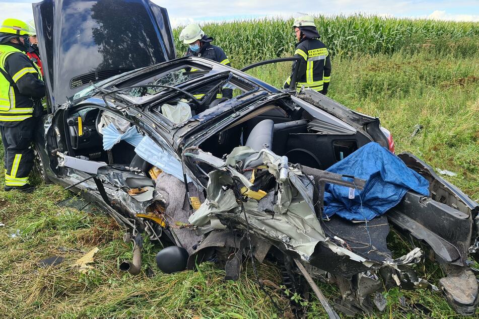 Niedersachsen, Bersenbrück: Das Wrack des Autos liegt nach dem Zusammenstoß mit einem Personenzug an einem beschrankten Bahnübergang auf einem Feld neben den Gleisen.