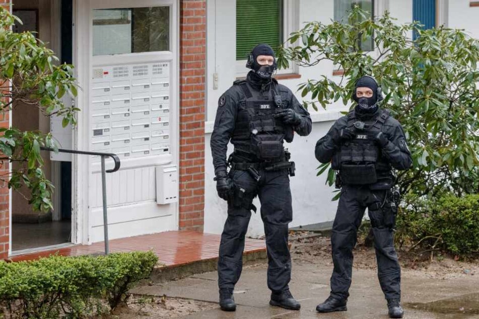 Zwei SEK-Beamte stehen während einer Razzia vor einem Hauseingang.
