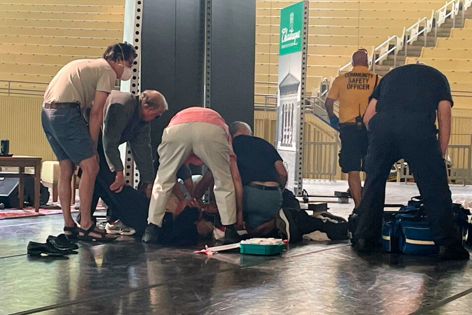 Nach dem Angriff liegt Salman Rushdie am Boden und wird von Helfern versorgt.