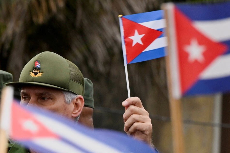 President Miguel Diaz-Canel waves a Cuban flag during a march outside the US Embassy in Havana to denounce as American aggression in the region on January 16, 2026.