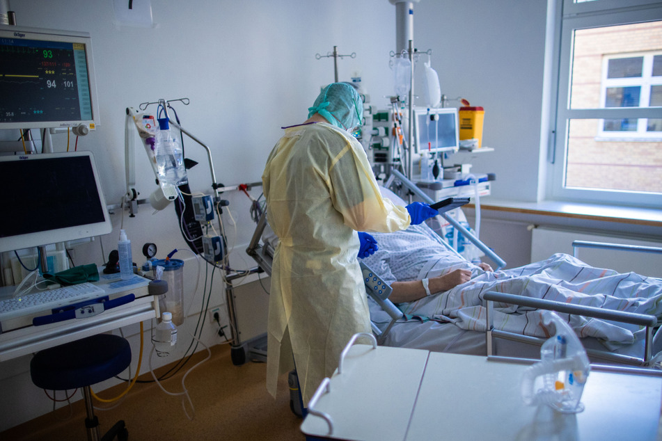 Ein Mitarbeiter behandelt im besonders geschützten Teil einer Intensivstation einen Covid-19-Patienten.