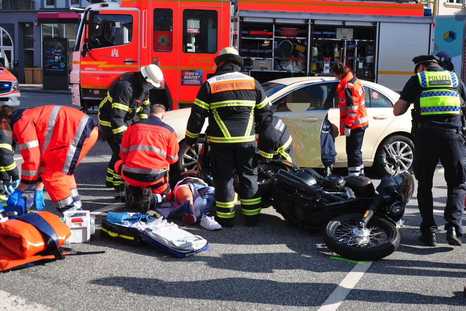 Rettungskräfte am Unfallort. Der verletzte Motorradfahrer liegt verletzt auf der Straße.