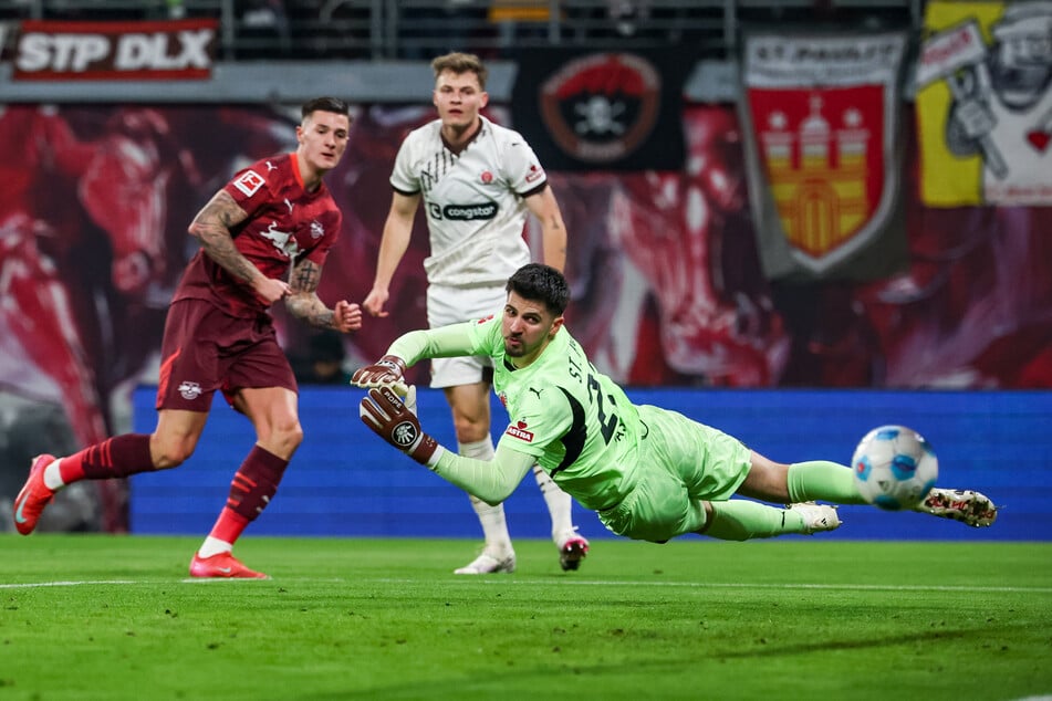 Leipzigs Benjamin Sesko (21) trifft gegen St. Paulis Nikola Vasilj (29) zum 1:0.