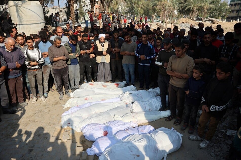 Palestinians recite a prayer over the bodies of victims killed in Israeli strikes at a cemetery in Jabalia in the northern Gaza Strip on November 10, 2024.