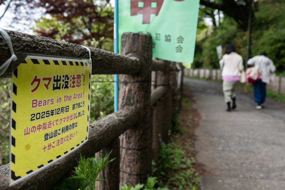 Bear attacks have increased significantly in the last year. Hikers walk past a sign warning of bears in the area in Ome, Tokyo.