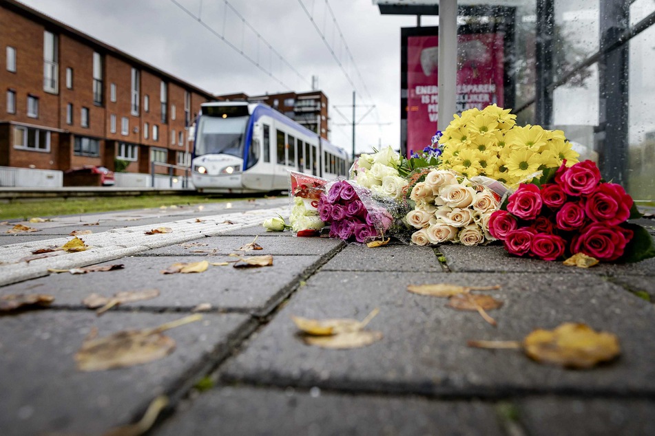 Blumen liegen an der Straßenbahnhaltestelle: Drei Jugendliche sollen in den Niederlanden einen Obdachlosen vor eine Straßenbahn gestoßen und so dessen Tod verschuldet haben.