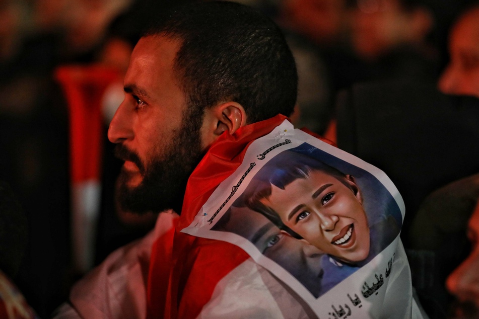 A soccer fan at the Africa Cup of Nations tournament displaying a photo of Rayan during a game.