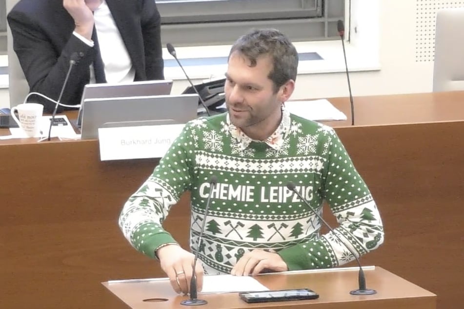 SPD-Stadtrat Christopher Zenker stellte den gemeinsamen Antrag der Linken und SPD im weihnachtlichen Chemie-Leipzig-Pulli vor.