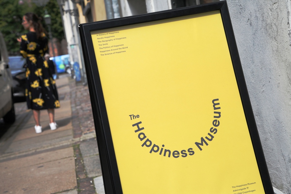 Eine Frau in einem geblümten Kleid steht vor dem Happiness Museum in Kopenhagen.