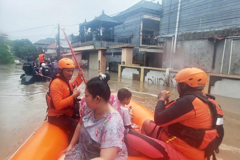 Retter evakuieren in einem Schlauchboot Bewohner aus ihrem überfluteten Haus in Denpasar, Bali.