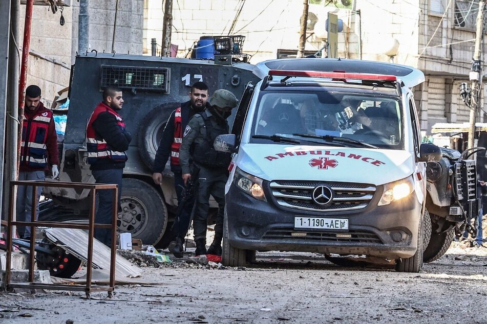 Palestinian paramedics look on as Israeli troops search an ambulance at a road block during an Israeli military raid in Jenin in the occupied West Bank.